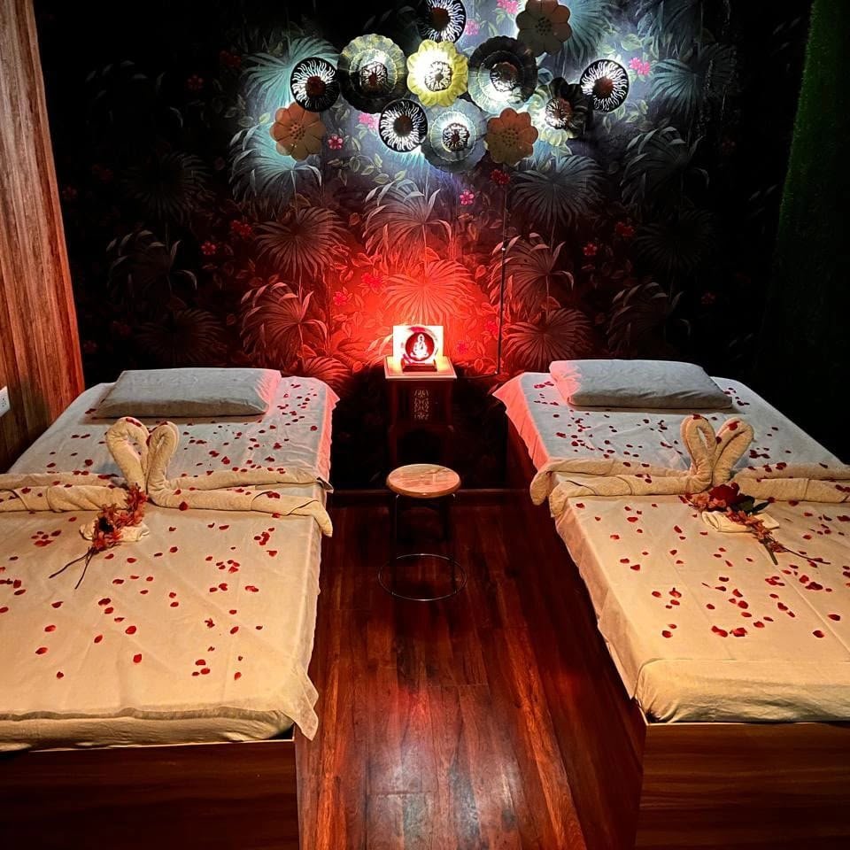 Couple spa suite at Lavella Wellness — two beds set with rose petals, towel swans and intimate red candlelight