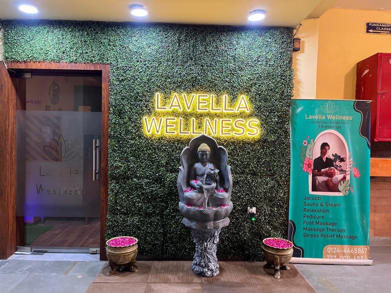Lavella Wellness entrance — neon sign, Buddha fountain with rose petals and frosted glass door