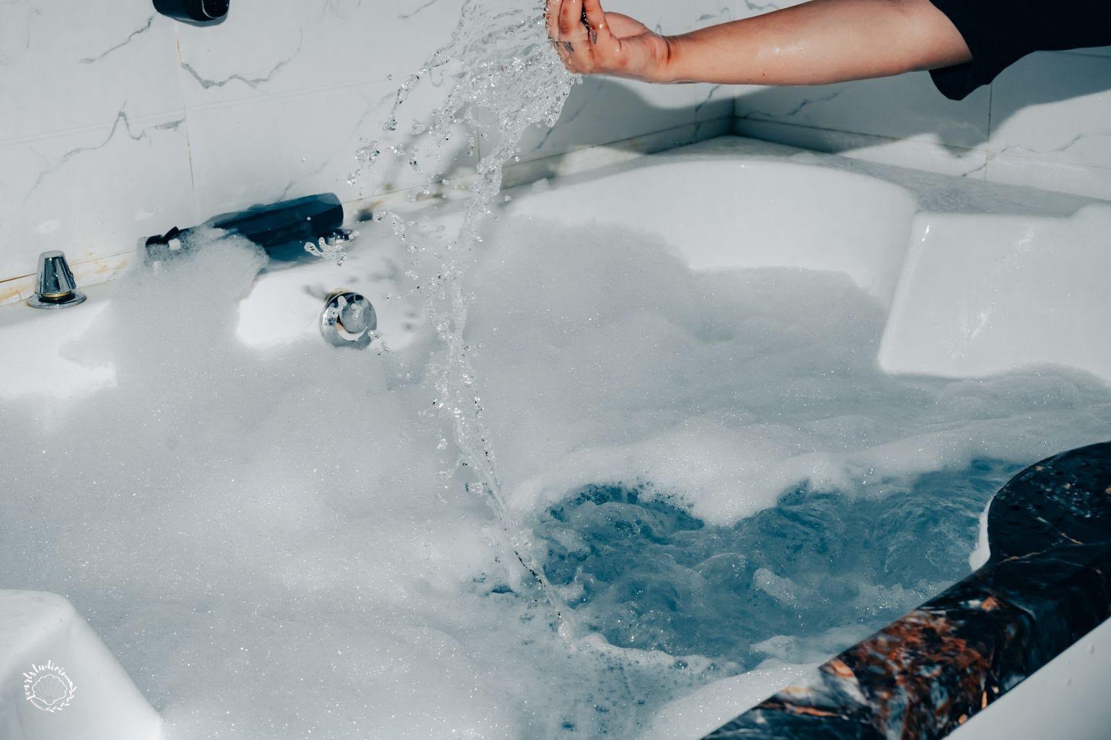 Water poured into the Lavella Wellness jacuzzi — bubbles forming in the marble hydrotherapy tub