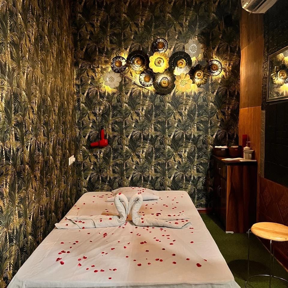 Tropical suite at Lavella Wellness — rich botanical wallpaper, towel swans and rose petals scattered in a heart
